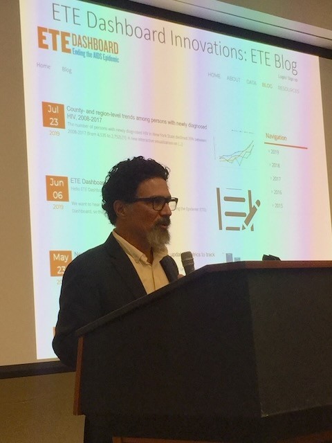 Denis Nash speaking at a podium in front of a slide about the ETE Dashboard